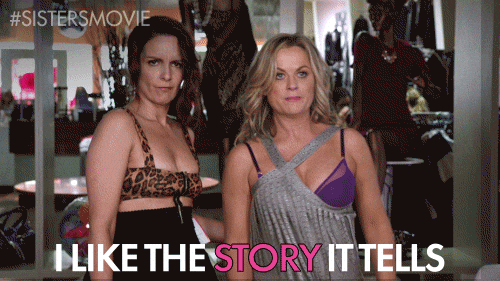 Two women stand in a lingerie shop wearing bras over their clothes, confidently posing for the camera. Captions like "I like the story it tells" make this image perfect for social media posts. The hashtag #SISTERSMOVIE appears in the corner.