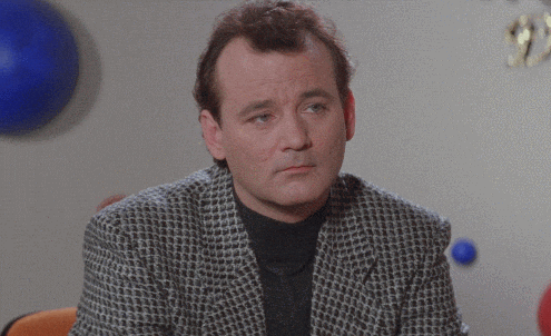 A man in a patterned blazer sits at a table, rolling his eyes and glancing to the side with an unimpressed expression—perhaps doubting the power of catchy headlines. Blue and gold decorations can be seen in the background.