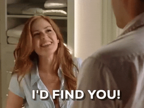 A smiling woman with long red hair says, "I'D FIND YOU!" to someone off-screen, in a warmly lit room with folded towels in the background—like catching PR Pitches in unexpected places.